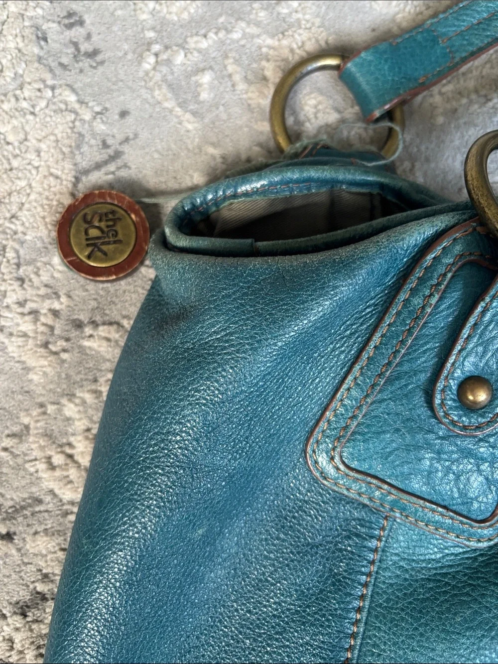 The Sak Teal Leather Shoulder Bag distressed has been loved and used.